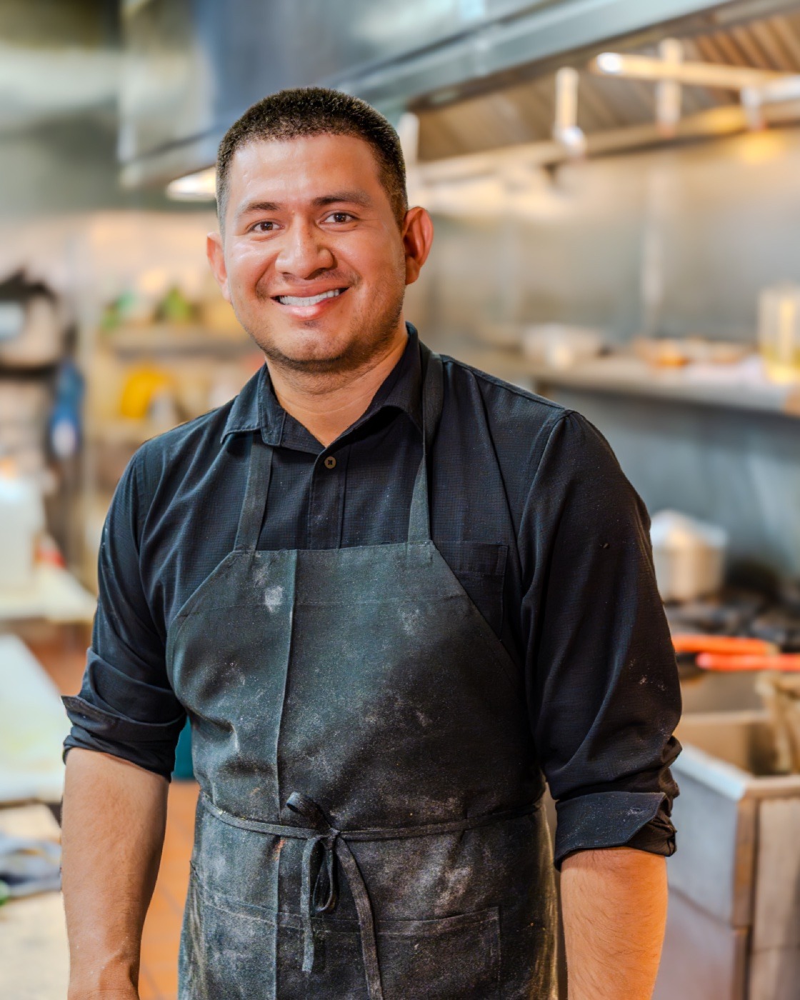 A Tandoori Kitchen chef smiling in the kitchen.