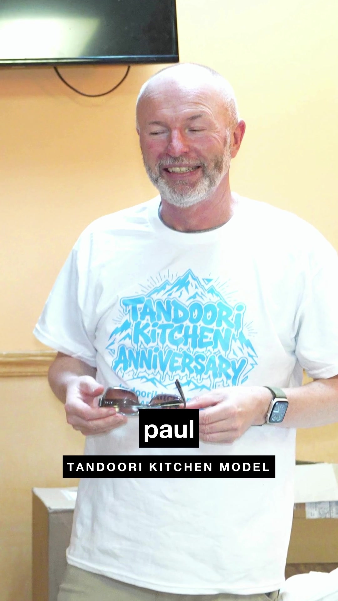 A longtime guest smiling at his table at Tandoori Kitchen, a still from the video series.